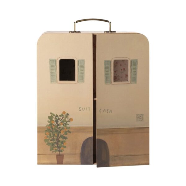 Ein kleiner Koffer, der mit einem bemalten Wandbild verziert ist, das eine Szene mit einem Haus, einer Pflanze und Fenstern zeigt.